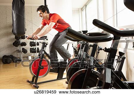 Man using stationary bicycle at gym View Large Photo Image Stock Photo - Man using stationary bicycle at gym. Fotosearch