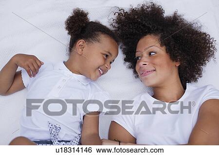 Mother and daughter laying on bed View Large Photo Image Stock Photograph - Mother and daughter laying on bed. Fotosearch