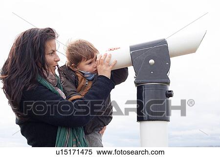 Stock Photography - Mother and son looking through telescope. Fotosearch