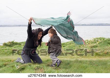 Stock Photo - Mother and son playing in grassy field. Fotosearch