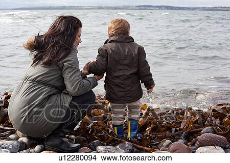 Mother and son playing on rocky beach View Large Photo Image Picture - Mother and son playing on rocky beach. Fotosearch