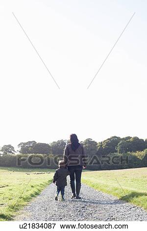 Mother and son walking on dirt road View Large Photo Image Stock Photo - Mother and son walking on dirt road. Fotosearch