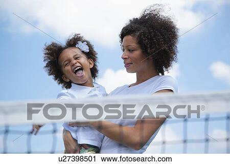 Mother holding daughter on tennis court View Large Photo Image Stock Image - Mother holding daughter on tennis court. Fotosearch