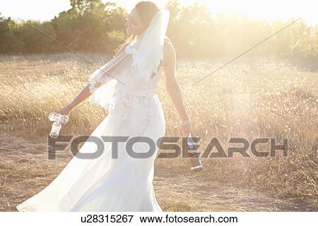 Newlywed bride carrying champagne View Large Photo Image Stock Photo - Newlywed bride carrying champagne. Fotosearch