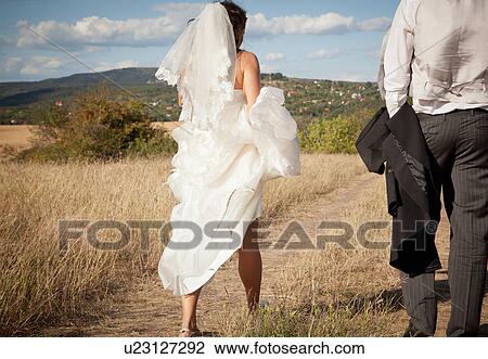 Newlywed bride holding up dress in grass View Large Photo Image Stock Image - Newlywed bride holding up dress in grass. Fotosearch
