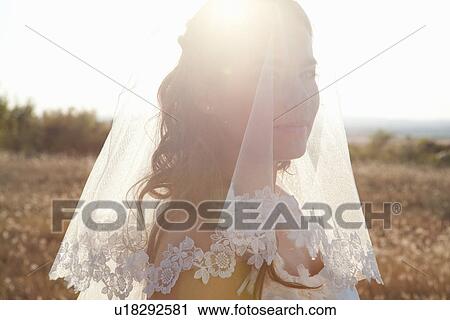 Stock Image - Newlywed bride standing outdoors. Fotosearch