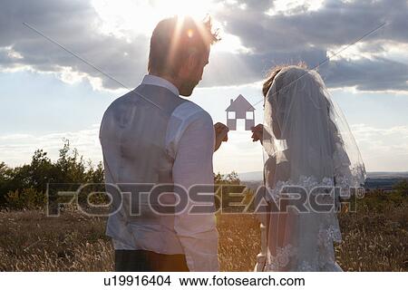 Newlywed couple holding a picture of a house View Large Photo Image Picture - Newlywed couple holding a picture of a house. Fotosearch