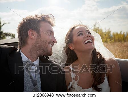 Stock Photo - Newlywed couple sitting in convertible. Fotosearch