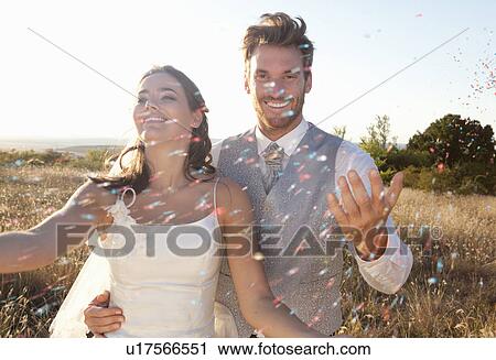 Stock Image - Newlywed couple walking in confetti. Fotosearch