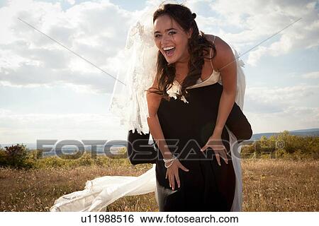 Newlywed groom carrying bride outdoors View Large Photo Image Stock Photograph - Newlywed groom carrying bride outdoors. Fotosearch