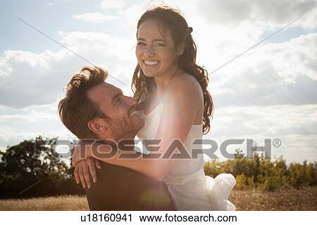 Newlywed groom holding bride outdoors View Large Photo Image Stock Image - Newlywed groom holding bride outdoors. Fotosearch