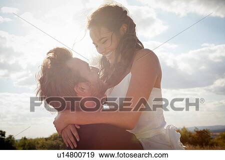 Newlywed groom holding bride outdoors View Large Photo Image Stock Photo - Newlywed groom holding bride outdoors. Fotosearch