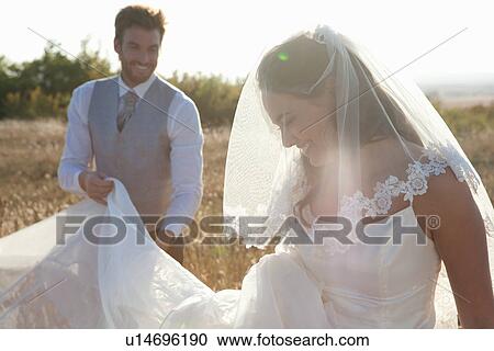 Newlywed groom holding brides dress View Large Photo Image Stock Image - Newlywed groom holding brides dress. Fotosearch
