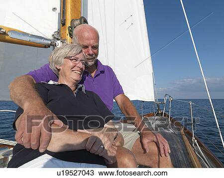 Stock Image - Older couple relaxing on sailboat. Fotosearch