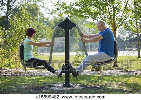 Stock Image - Older couple using exercise equipment. Fotosearch