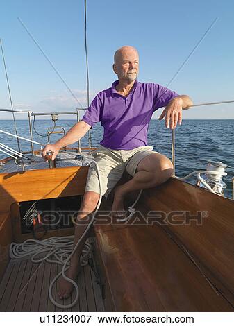 Stock Photo - Older man steering sailboat. Fotosearch