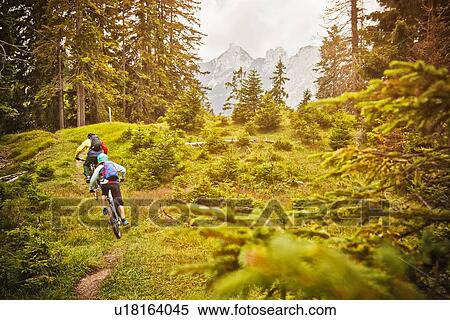 Stock Photography - People riding bicycles on dirt path. Fotosearch