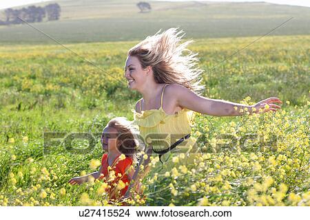 Picture - Sisters playing in field of flowers. Fotosearch