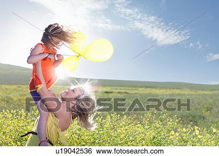 Stock Photograph - Sisters playing in field of flowers. Fotosearch