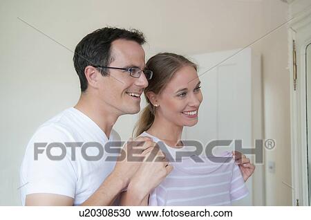 Smiling couple admiring sweater View Large Photo Image Stock Image - Smiling couple admiring sweater. Fotosearch