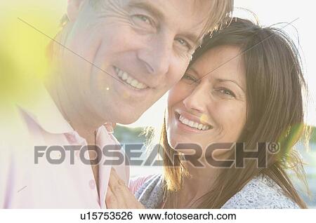 Stock Photograph - Smiling couple hugging outdoors. Fotosearch