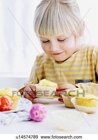 Stock Photo - Smiling girl admiring cupcake. Fotosearch