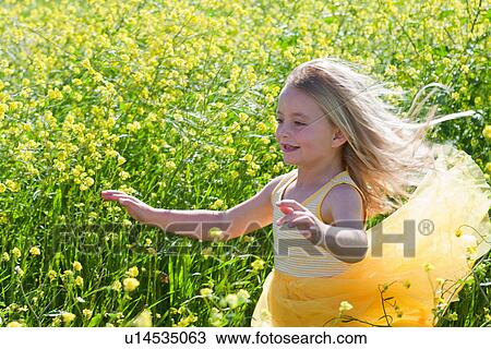 Stock Image - Smiling girl playing in field of flowers. Fotosearch