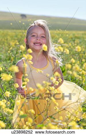 Stock Image - Smiling girl playing in field of flowers. Fotosearch