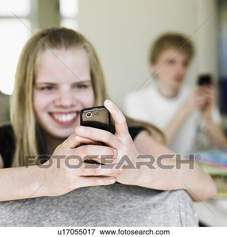 Stock Photo - Smiling girl using cell phone. Fotosearch