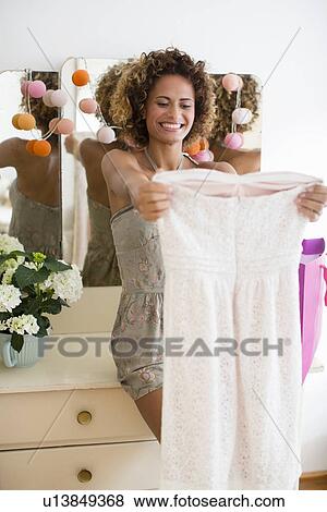 Stock Photo - Smiling woman admiring new dress. Fotosearch