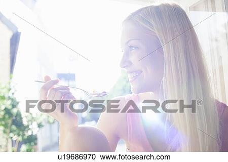 Smiling woman eating bowl of cereal View Large Photo Image Stock Image - Smiling woman eating bowl of cereal. Fotosearch