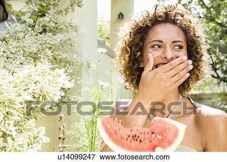 Stock Photo - Smiling woman eating watermelon. Fotosearch