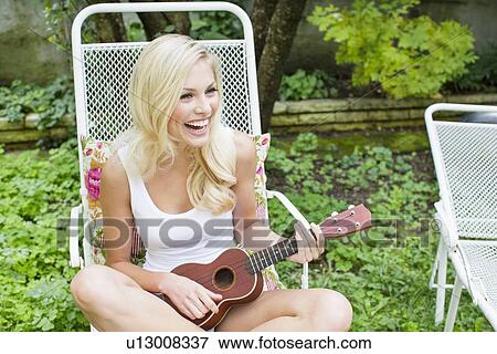 Stock Photo - Smiling woman playing ukulele. Fotosearch