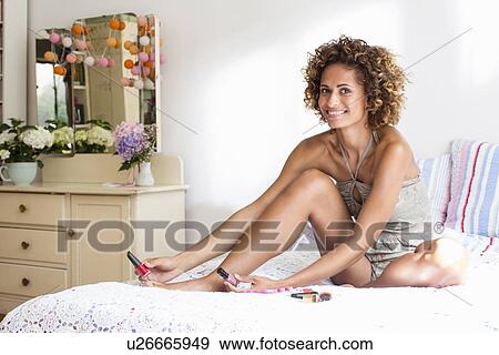 Stock Photo - Smiling woman polishing toenails. Fotosearch