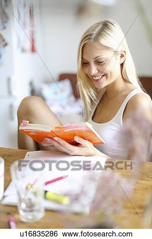 Smiling woman reading at desk View Large Photo Image Stock Photograph - Smiling woman reading at desk. Fotosearch