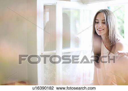 Smiling woman sitting in windowsill View Large Photo Image Stock Image - Smiling woman sitting in windowsill. Fotosearch