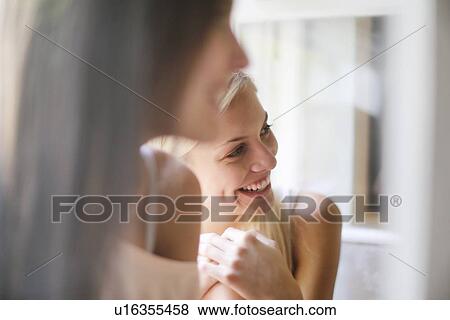 Stock Photo - Smiling woman sitting with friend. Fotosearch