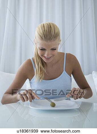 Stock Photo - Smiling woman slicing olive on plate. Fotosearch