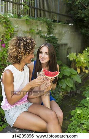 Stock Photograph - Smiling women eating watermelon. Fotosearch