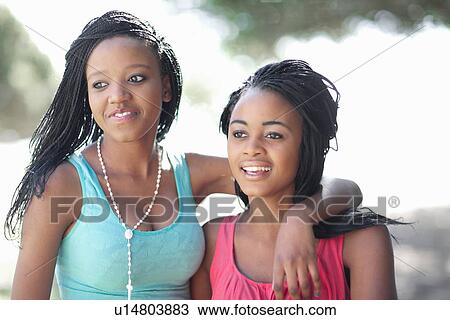 Stock Image - Smiling women hugging outdoors. Fotosearch