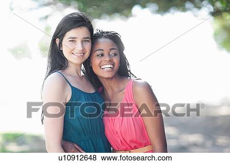 Stock Photo - Smiling women hugging outdoors. Fotosearch