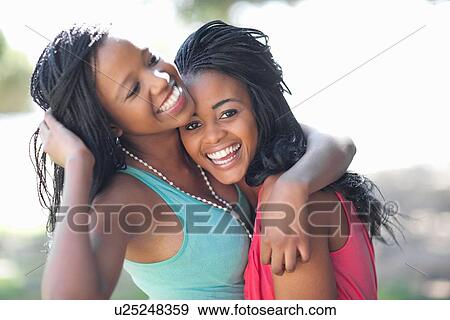 Stock Photo - Smiling women hugging outdoors. Fotosearch
