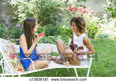 Stock Image - Smiling women relaxing in backyard. Fotosearch
