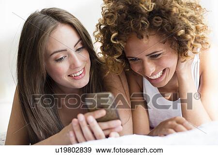 Stock Photo - Smiling women using cell phone. Fotosearch