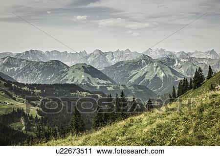 Snowy mountains and grassy hillside View Large Photo Image Stock Image - Snowy mountains and grassy hillside. Fotosearch