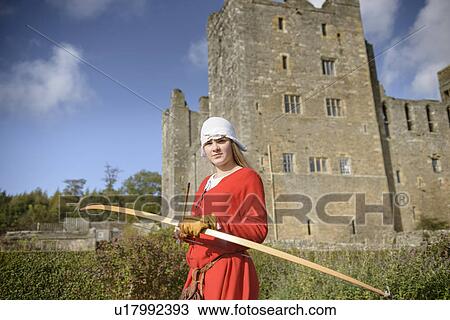 Stock Image - Student in period dress holding bow. Fotosearch