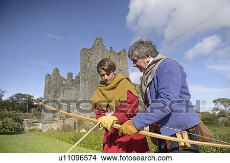 Picture - Student in period dress shooting arrow. Fotosearch