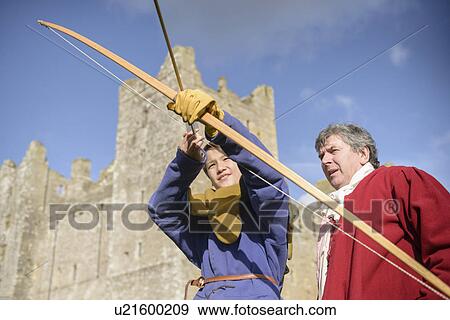 Stock Photo - Student in period dress shooting arrow. Fotosearch