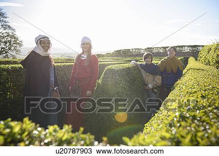 Stock Image - Students in period dress in hedge maze. Fotosearch