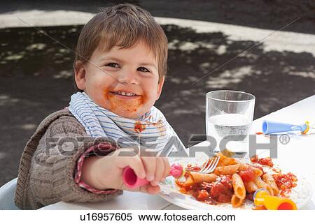 Stock Photography - Toddler boy eating pasta outdoors. Fotosearch
